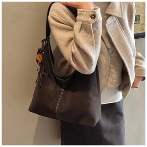Detail of vintage matte brown tote bag with white contrast stitching and floral charm