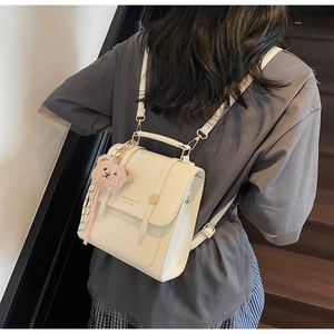 Detail of cream faux crocodile backpack with plush bear charm and MIKAIXIQI branding