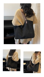 Detail of black suede tote bag with brown leather straps and metal buckle connection