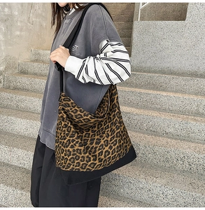 Close-up of leopard print canvas tote bag featuring black stitching and wide shoulder strap