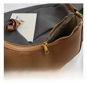 Detail of high-quality golden zipper and chevron pattern lining on brown crescent bag