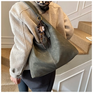 Detail of olive green matte leather tote bag featuring decorative beads and fashion tag