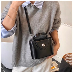 Détail du mini sac trapèze noir avec fermoir rotatif argenté et bandoulière amovible