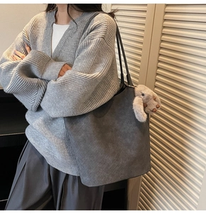 Detail of grey woven tote bag with smooth matte texture and cute plush rabbit charm
