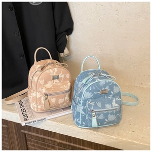 Detailed view of mini backpacks with white tulip patterns in apricot and blue fabric