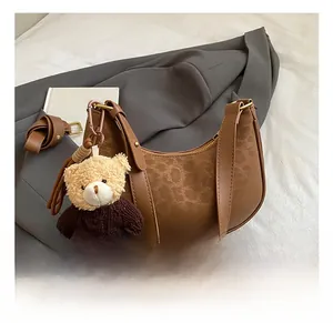 Detail of vintage brown crescent hobo bag with embossed texture and cute bear pendant