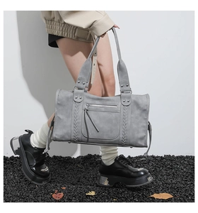 Detailed view of grey vintage travel bag with woven lines, silver rivets, and zip pockets