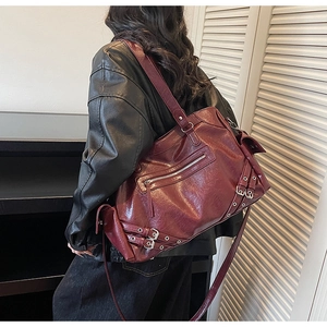Detail of vintage burgundy tote bag featuring metallic buckles and glossy faux leather texture