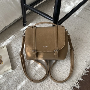 Detailed view of the tan synthetic leather bag showing dual buckles and top handle