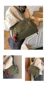 Detail of dark green leather tote bag featuring a gold buckle and brown bear charm