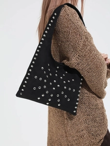 Sac hobo noir tendance en daim avec rivets argentés porté sur un pull en maille marron
