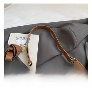 Detail of brown leather shoulder bag with gold hardware and a cute beige plush bear charm