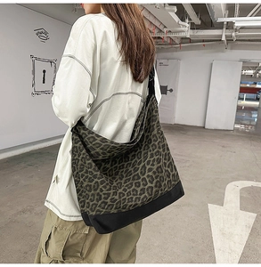 Detail shot of the large leopard print canvas crossbody bag worn by a model in a casual setting