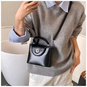 Détail du sac à main trapèze en cuir noir avec fermoir rotatif argenté et bandoulière