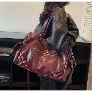 Detail of dark red tote bag with metallic buckles and glossy faux leather texture