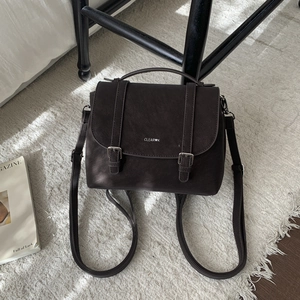 Close-up of deep brown vintage faux leather backpack with metallic buckles and logo