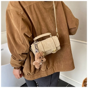 Dettaglio della borsa a cilindro beige con ciondolo a forma di orso e fibbia in metallo