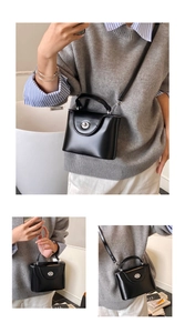 Détail du mini sac boîte noir mat montrant le fermoir argenté et la bandoulière