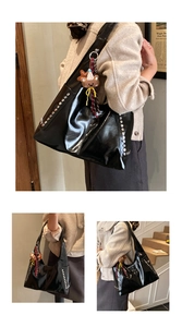 Detail of glossy black tote bag featuring silver studs and a cute bear charm accessory