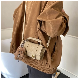 Detail der aprikosenfarbenen Boston-Tasche mit Drehverschluss und Plüsch-Anhänger