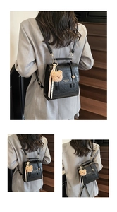 Detail of black crocodile pattern backpack with gold clasp and brown plush bear charm