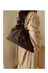 Detail view of large dark brown suede tote bag with matching card holder on trench coat