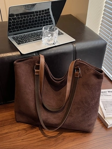Brown suede tote bag for women featuring premium leather straps in a minimal office setting