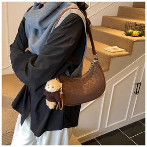 Chic leopard print crescent underarm bag with bear pendant and leather strap detail