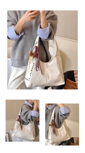 Detail of white glossy leather hobo bag with silver studs and plush tassel accessory