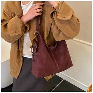 Detail of dark reddish-brown matte tote bag with white stitching and wood bead charms