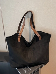 Minimalist black suede tote bag with brown leather handles on design books for work
