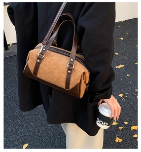 Detail of vintage brown suede boston bag with leather handles and metallic rivets