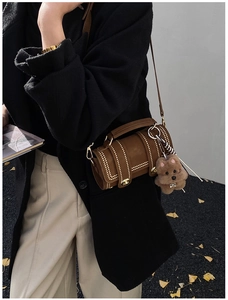 Borsa a cilindro marrone vintage con borchie dorate e ciondolo a orso portata da modella