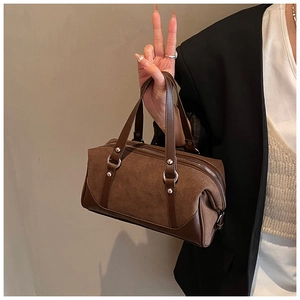 Detail of dark brown suede Boston bag with smooth leather handles and metal rivets
