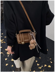 Dettaglio borsa Boston scamosciata marrone con borchie dorate e ciondolo a forma di cane