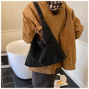 Detail of black suede Hobo bag with white contrast stitching and a wooden clover charm