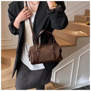 Detail of a brown suede bowling tote bag with leather trim on model near stairs