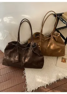 Detail of soft suede tote bags in dark coffee and caramel colors with side pouches
