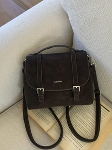 Vintage dark brown large capacity crossbody bag with buckle detail on a sofa