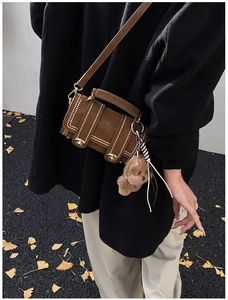 Dettaglio della borsa Boston vintage marrone con borchie dorate e ciondolo orsetto