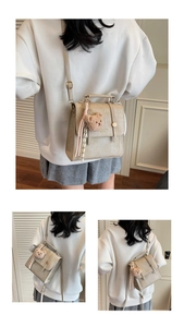 Detail of beige faux crocodile leather bag with cute bear charm and tassel decoration