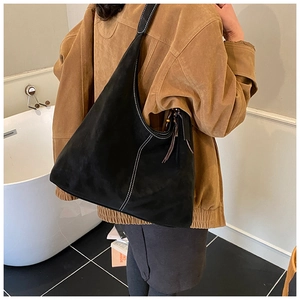 Detail of black large Hobo bag featuring white contrast stitching and tassel charm