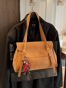 Brown retro tote bag with bear charm hanging on a black blazer for work and daily style