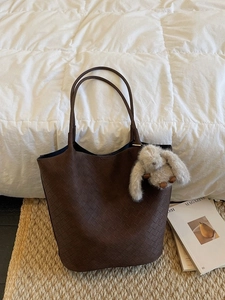 Vintage brown woven checkerboard tote bag with cute plush rabbit charm on woven mat