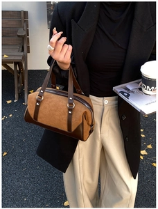 Brown suede Boston tote bag with dual handles shown on an outdoor wooden bench