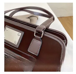 Detail of white contrast stitching and silver hardware on a brown suede tote bag