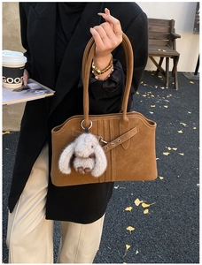 Close-up of brown suede tote bag featuring a cute bunny pendant and stylish buckle detail