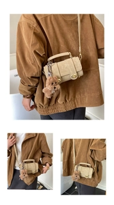 Detail der beigen Boston Tasche mit Vintage-Metallschloss und Plüsch-Hundeanhänger