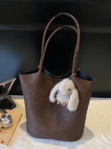 Brown woven leather tote bag with long handles and a cute plush bunny pendant on side