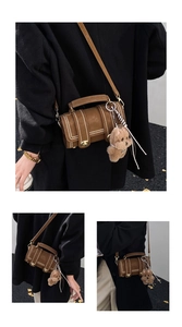 Nahaufnahme der braunen Vintage-Tasche mit Goldnieten und einem süßen Plüsch-Hundeanhänger
